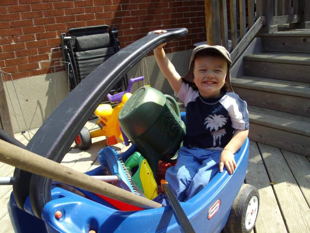 Smiling child in a wagon full of toys.