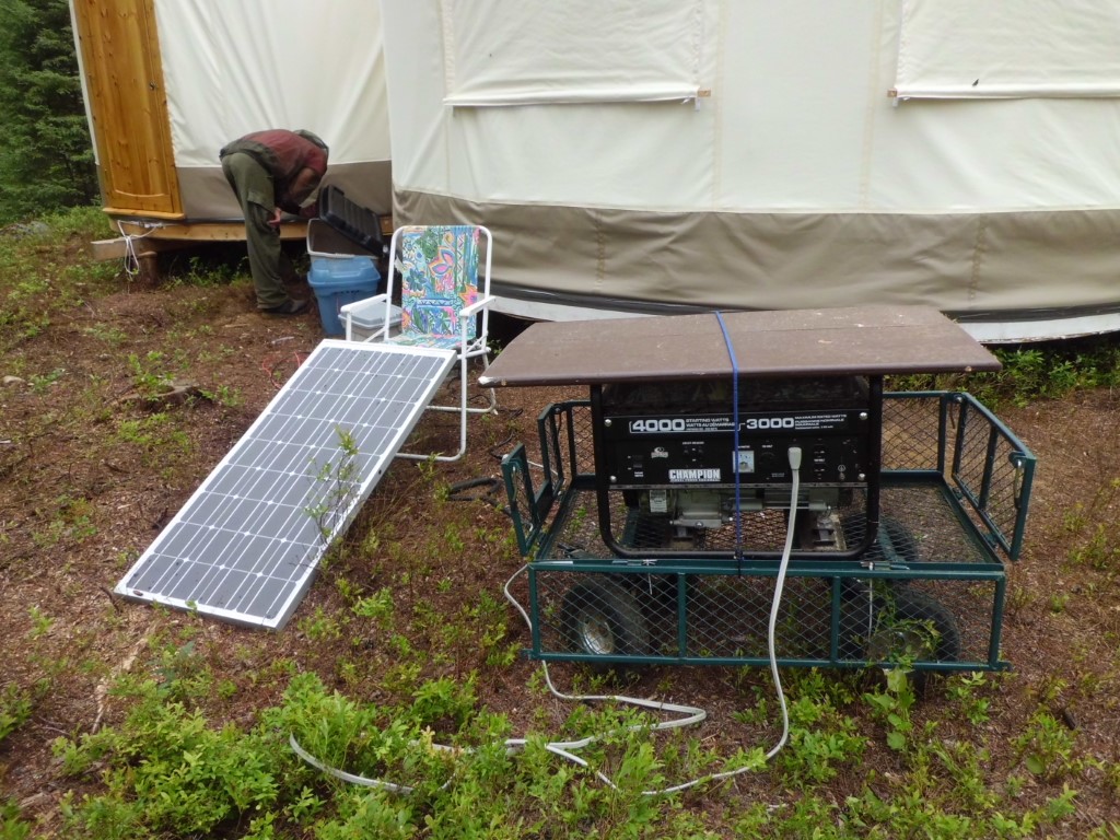 A solar panel on a chair, a generator covered by a plank