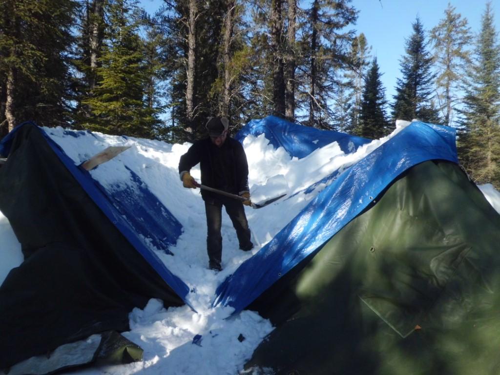 Man shovelling off a tent collapsed by snow.