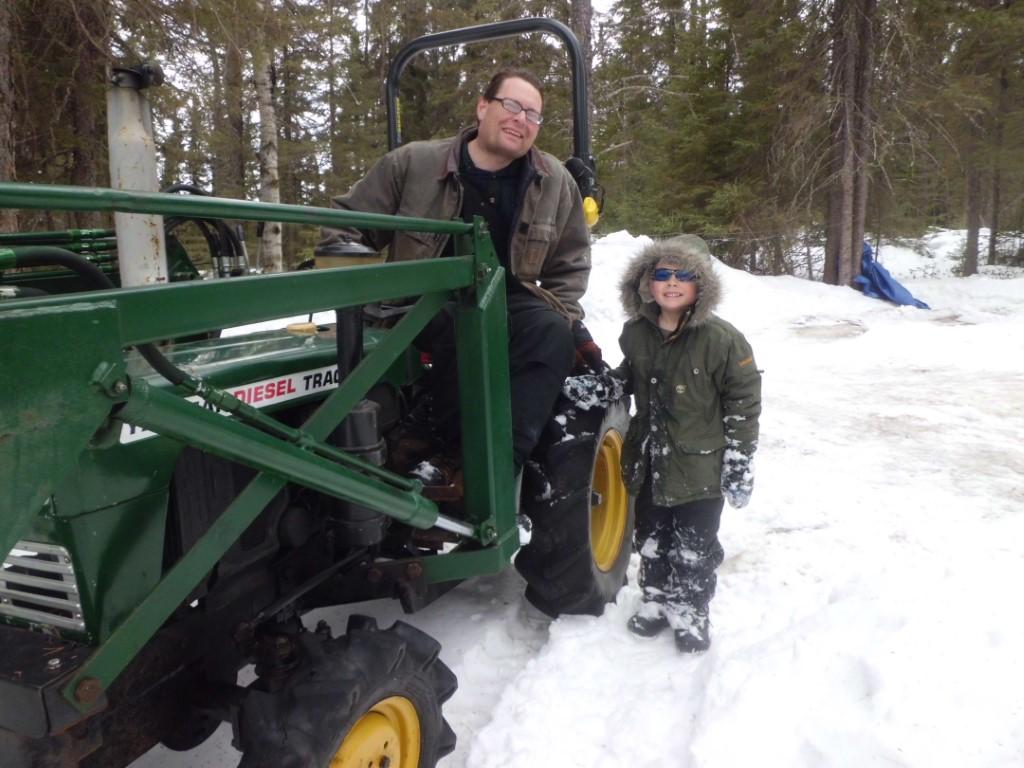 Man and boy posed with Yanmar tractor in winter.